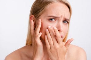Femeie tânără inspectându-și îngrijorată fermitatea pielii
